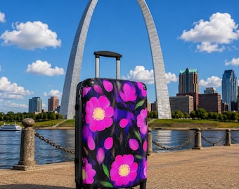 May include: A rolling suitcase featuring a vibrant floral pattern with bright pink flowers, yellow centers, and green leaves set against a dark, brush-stroked background. The luggage has a black frame, a retractable handle, and four wheels.