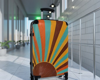 May include: A colorful suitcase with a retro sunburst design in shades of orange, yellow, brown, and blue. The suitcase has black wheels and a black handle.
