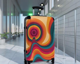 May include: A hard-shell rolling suitcase featuring a vibrant, multi-colored graphic pattern of concentric circles and wavy, flowing lines in shades of orange, yellow, teal, and deep magenta, equipped with a black telescopic handle and four wheels.