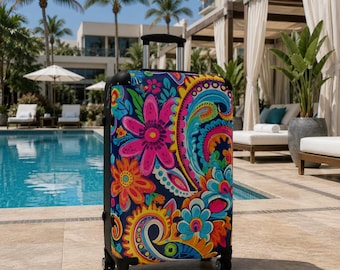 May include: A rolling suitcase featuring a vibrant, multi-colored floral and paisley pattern on a dark blue background. The luggage has a retractable silver handle, black corner protectors, and four black spinner wheels for mobility.
