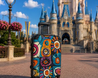 May include: A rolling suitcase featuring a vibrant, multi-colored abstract pattern of circles and floral-like shapes in shades of orange, blue, purple, and yellow. The luggage has a black frame, a retractable handle, and four spinner wheels.
