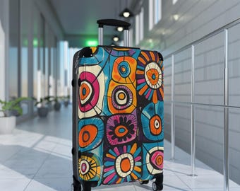 May include: A rolling suitcase featuring a vibrant, multi-colored abstract pattern of circular and floral-like shapes in shades of orange, blue, pink, and yellow. The luggage has a black frame, a retractable handle, and four wheels for mobility.
