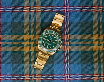 May include: A gold-tone wristwatch featuring a vibrant green dial and a matching green rotating bezel. The watch has a metallic gold link bracelet and displays the brand name Betsey Johnson on the face with luminous hour markers and hands.