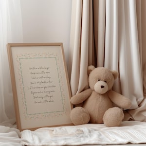 Op de afbeelding: Een ingelijste print met een gedicht en een teddybeer. De print heeft een licht houten frame en een crèmekleurige achtergrond met een bloemenrand. De teddybeer is lichtbruin en zit op een witte deken.