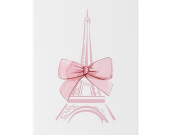 May include: A pink watercolor print of the Eiffel Tower adorned with a large pink bow. The artwork is set against a white background, creating a soft and feminine aesthetic. The image is a vertical rectangle.
