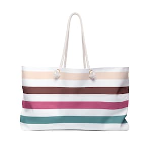 May include: A white striped tote bag with brown, pink, and teal stripes. The bag has white rope handles.