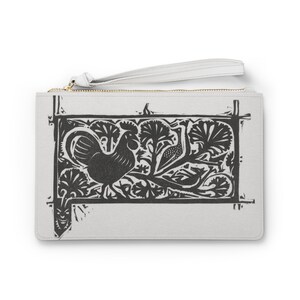 Puede incluir: Una cartera de mano blanca con un diseño de gallo y flores en blanco y negro impreso en la parte delantera. La cartera tiene una cremallera y una correa de muñeca.