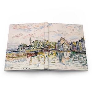 May include: An open journal featuring a watercolor painting of a harbor scene. The artwork depicts boats, buildings, and reflections in the water, with a cloudy sky above. The artist's signature and date are visible at the bottom.