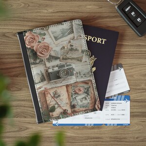 May include: A passport holder with a vintage design featuring a camera, roses, and old postcards. The holder is made of brown leather with a black trim.