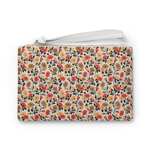 May include: A white zippered pouch with a floral pattern. The pattern features small red, orange, and brown flowers on a white background.
