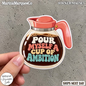 May include: A die-cut sticker or magnet shaped like a glass coffee carafe with a coral-colored lid and handle. The carafe is filled with dark brown coffee and features the text "POUR MYSELF A CUP OF AMBITION" in white, coral, and teal lettering.