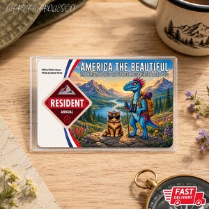 Puede incluir: Una tarjeta rectangular America the Beautiful National Parks and Federal Recreational Lands Pass con un dinosaurio azul con mochila y un gato con gafas de sol en un paisaje montañoso, con el texto Resident Annual y el título del pase.