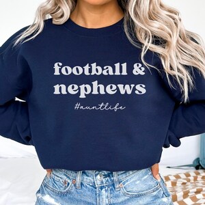 May include: Navy blue sweatshirt with the text "football & nephews #auntlife" in white.