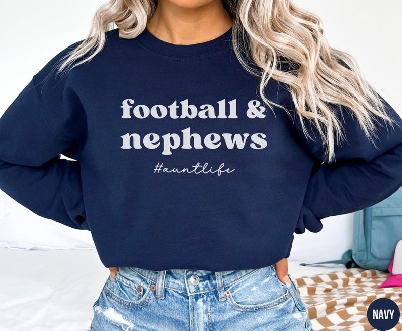 May include: Navy blue sweatshirt with the text "football & nephews #auntlife" in white.
