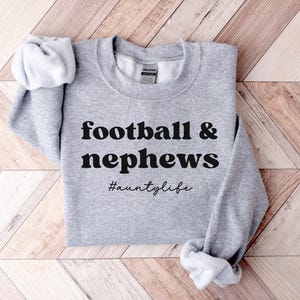 May include: Gray sweatshirt with the text "football & nephews #auntilyfe" printed in black.