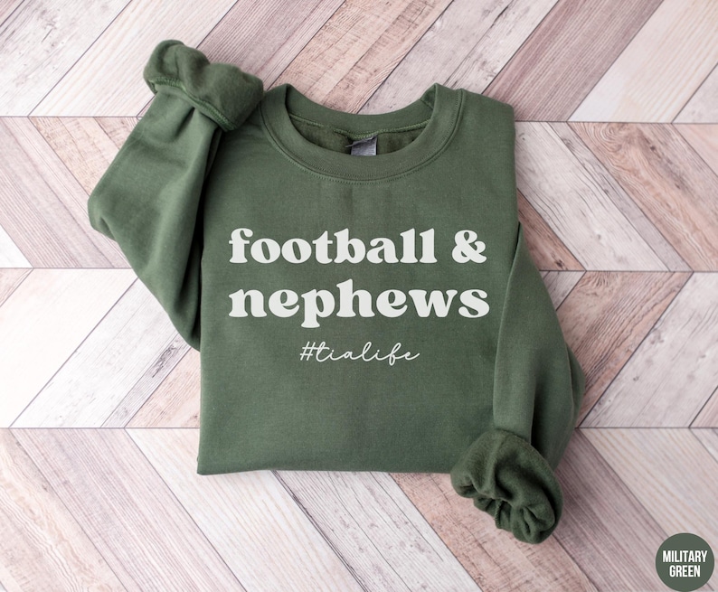 May include: A green sweatshirt with the text "football & nephews #tialife" in white.