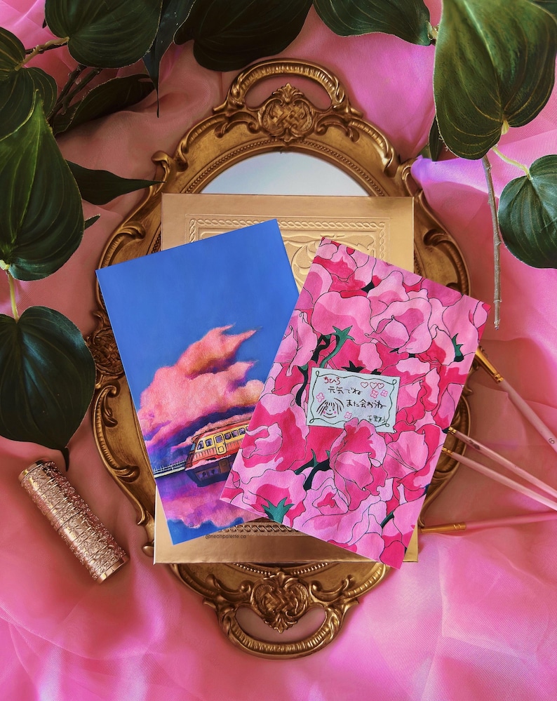 May include: Two postcards with a pink floral design and a blue sky with a pink cloud and a train reflecting in water. The text on the floral postcard says "石膏♡" and "永遠のあなたへ".
