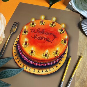 May include: A colorful illustration of a cake with lit candles. The cake is orange with the words "Welcome home!" written in red. The cake sits on a yellow plate with a decorative edge. Two yellow candles and a gold fork are also visible.