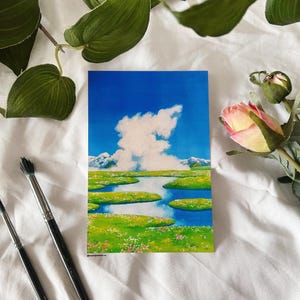 May include: A watercolor painting of a landscape with a large white cloud in a blue sky, a green field with a winding blue river, and snow-capped mountains in the distance.