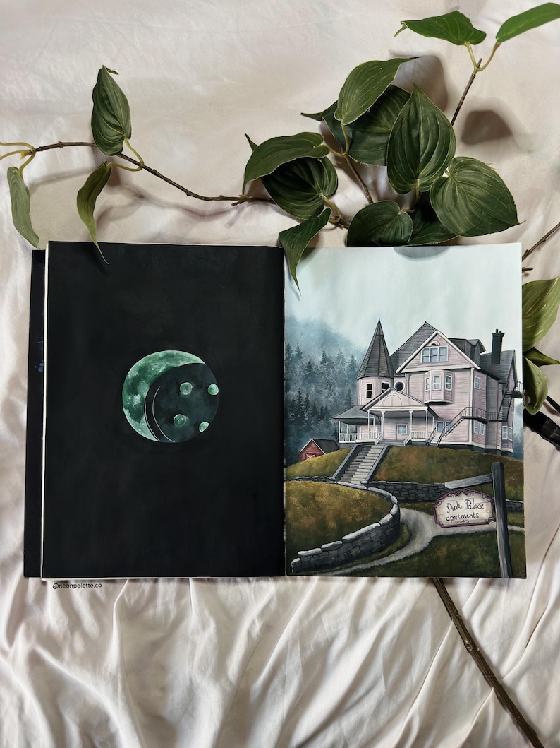 May include: A hand-painted illustration of a pink house with a sign that reads "Pink Palace Apartments". The house is surrounded by trees and a stone wall. The illustration is on the right page of an open sketchbook. The left page of the sketchbook is black with a green moon.