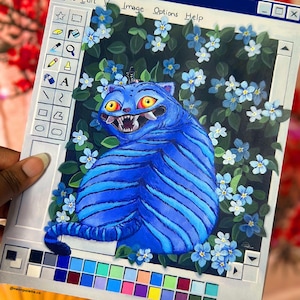 May include: A painting depicting a blue tiger-like creature with yellow eyes and sharp teeth, surrounded by blue flowers and green leaves. The artwork is framed within a retro computer window, labeled "SAJA-Paint". A color palette is visible at the bottom.