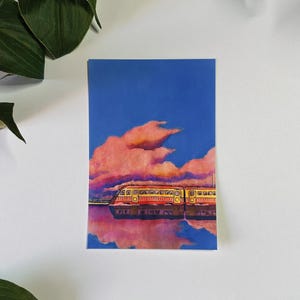 May include: A painting of a yellow and red train traveling through a pink and blue sky with fluffy clouds. The train is reflected in the water below.