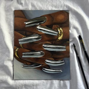 Op de afbeelding: Een schilderij van handen met lange, chroomkleurige nagels en gouden ringen. Het kunstwerk toont een close-up van de handen, waarbij de nagels het licht reflecteren. De achtergrond is een zachte, neutrale kleur en de handtekening van de kunstenaar is zichtbaar.