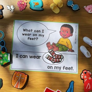 May include: An educational card for children with the text "What can I wear on my feet?" and "I can wear on my feet." The card features a cartoon illustration of a child and socks. Various miniature shoe charms surround the card.