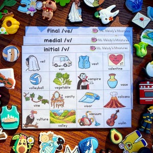 Puede incluir: Una colección de imanes y tarjetas didácticas coloridas. Las tarjetas didácticas presentan ilustraciones y palabras como "velo", "furgoneta", "chaleco", "voleibol", "vegetal", "vampiro", "san valentín", "jarrón", "vid", "buitre", "valle", "visera", "aspiradora", "volcán" y "violín".