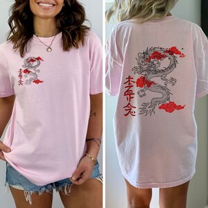 May include: Pink oversized t-shirt with a black and red dragon graphic and the text "本命 天" on the back. The front of the shirt has a smaller version of the dragon graphic and the same text.