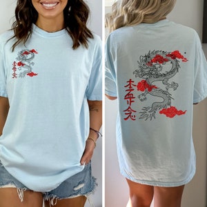 May include: A light blue t-shirt with a black and red dragon graphic and Japanese characters on the front and back. The characters on the front say "本命天" and the characters on the back say "本命天".