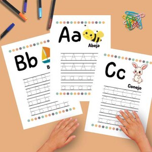 May include: Three white letter tracing worksheets with the letters A, B, and C. Each sheet has a colorful border and a corresponding image: a bee, a sailboat, and a rabbit. Pens and paperclips are also visible.