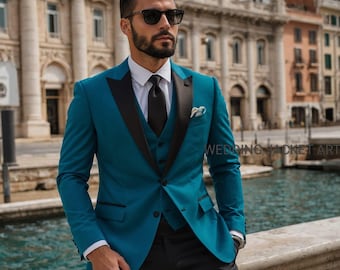 Può includere: Un completo a tre pezzi color teal con revers neri e cravatta nera. Il completo comprende giacca, gilet e pantaloni. L'uomo nell'immagine indossa occhiali da sole e una camicia bianca. Lo sfondo presenta uno specchio d'acqua e degli edifici.