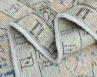 May include: Close-up of a beige and brown patterned rug with a white fringe. The rug is woven with a variety of textures and colors, creating a unique and interesting design.