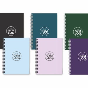 Könnte beinhalten: Eine Sammlung von sechs Spiralnotizbüchern in verschiedenen Farben: Schwarz, Türkis, Tannengrün, Hellblau, Lavendel und Lila. Jedes Notizbuch trägt den Text "THE GYM LOG" in einem weißen Kreis auf dem Einband. Die Notizbücher sind ordentlich angeordnet.