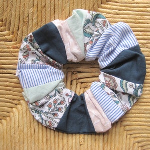 Puede incluir: Un scrunchie de pelo de tela colorido con un patrón floral y rayas en tonos azules, rosas y verdes.