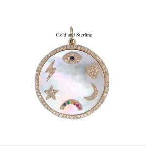 Peut inclure: Pendentif en or et argent sterling avec un disque rond en nacre blanche. Le disque est décoré d'un éclair, d'une étoile, d'un cœur, d'un mauvais œil, d'un croissant de lune et d'un arc-en-ciel. Le pendentif est entouré d'un cercle de petits diamants.