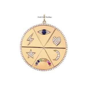 May include: Gold pendant necklace with a round charm featuring five different symbols: an evil eye, a lightning bolt, a heart, a star, and a crescent moon. The charm is set with diamonds and colorful gemstones.