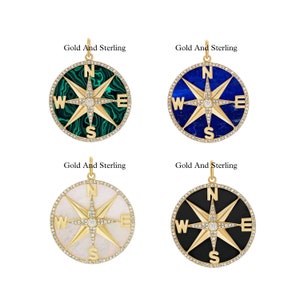 May include: Four gold compass pendants with different colored stones. The stones are green, blue, white, and black. Each compass has a diamond in the center and the letters N, S, E, and W around the edge.