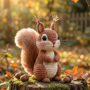 Op de afbeelding: Een gehaakte eekhoorn in bruin- en crèmetinten zit op een met mos begroeide boomstronk, omringd door eikels en herfstbladeren. De eekhoorn heeft een pluizige staart, roze wangen en zwarte ogen. De achtergrond is wazig.