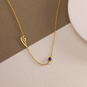 May include: A gold chain necklace with a single wing pendant and a small purple gemstone.