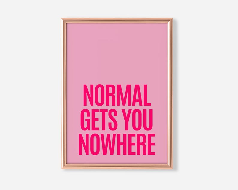 May include: A framed pink art print with the words "NORMAL GETS YOU NOWHERE" in bold, hot pink letters. The print has a light pink background and a thin, gold-colored frame. The artwork is a motivational piece.