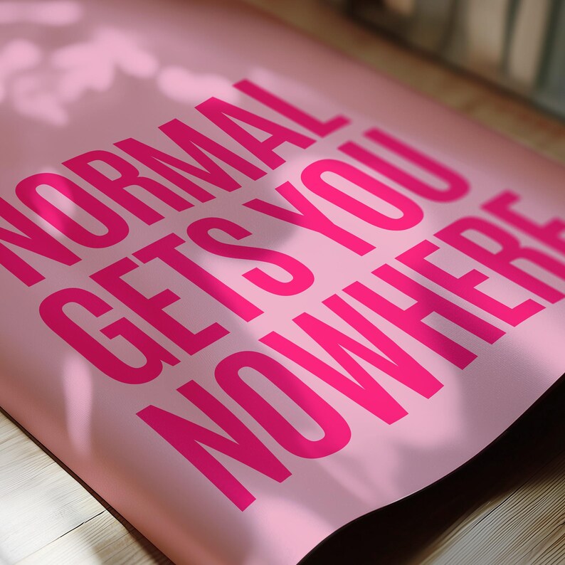 May include: A pink poster with the words "NORMAL GETS YOU NOWHERE" printed in bright pink. The poster is slightly curled, and the text is large and bold.