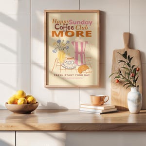 Puede incluir: Un estampado enmarcado con las palabras "Happy Sunday Coffee Club MORE" en naranja y rosa. El estampado presenta una cafetera, una taza, un cruasán y flores. Un cuenco de madera con limones, una tabla de cortar y una taza están en la encimera.