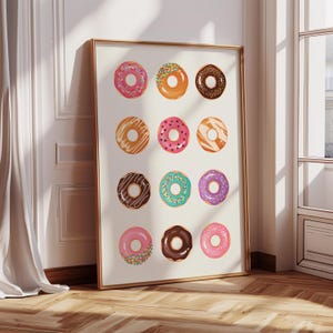 May include: A printable wall art design featuring a grid of 12 colorful donuts with various toppings, including sprinkles, chocolate, and frosting.