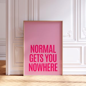 Könnte beinhalten: Ein gerahmter rosa Kunstdruck mit den Worten "NORMAL GETS YOU NOWHERE" in kräftigen, pinkfarbenen Buchstaben. Das Kunstwerk wird vor einer weißen Wand mit dekorativen Leisten und einem Holzboden präsentiert.