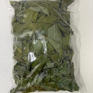 Puede incluir: Una bolsa de plástico transparente y resellable llena de una gran cantidad de hojas de laurel secas de color verde oscuro. Las hojas están enteras y fragmentadas, mostrando varias formas y tamaños, empaquetadas dentro de la bolsa.
