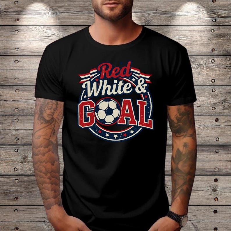 May include: Black t-shirt with a soccer ball graphic. The design features the words "Red White & GOAL" in red and white, with a soccer ball in the center. The design is surrounded by a blue circle with stars.
