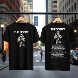 May include: A black t-shirt featuring the band name THE SCRIPT in white text above a black and white portrait of three band members. The back of the shirt displays the band name and a list of tour dates and venues from NOV 2 to DEC 22.