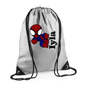 Puede incluir: Una bolsa de cord&oacute;n plateada con un dise&ntilde;o de Spider-Man de dibujos animados en rojo, azul y negro. El nombre "Iyla" est&aacute; impreso en negro en el lado derecho. La bolsa tiene cordones negros.